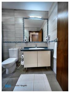 a bathroom with a sink and a toilet and a mirror at Weibdeh Heights Hotel Suites in Amman +60 photos