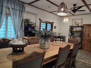 een eettafel met een vaas met bloemen erop bij Jam's Pool Villa Langkawi in Ulu Melaka