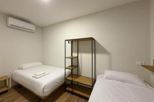 a bedroom with two beds and a glass cabinet at Hostal Alcorcón in Alcorcón