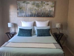 a bed with blue pillows and a painting above it at 5Viooltjie in Riversdale
