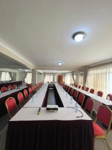 a conference room with a long table and red chairs at Kenendia Hotel in Kampala
