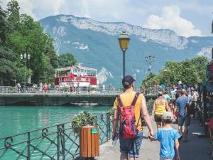 a man and a child walking down a sidewalk near a river at Beau T3 in Aiguebelle