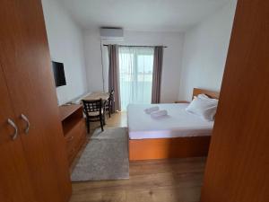 een slaapkamer met een bed, een bureau en een tafel bij Apartament DOM in Moşniţa Nouă