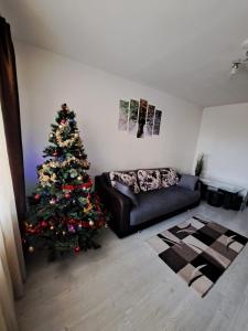 a christmas tree in a living room with a couch at Apartament VREvents in Deva