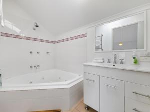 Un baño blanco con bañera y lavabo. en Cascades 15 - Amazing Lake Views l Spa Bath l Split Level Apt l Central Location l Wi-Fi, en Jindabyne 17 fotos más