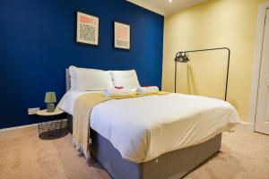 a blue bedroom with a bed with two stuffed animals on it at West Apartment in Coatbridge