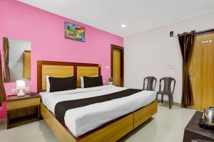 Hotel O Varanasi Trade Center formerly Vairaghi Villa في فاراناسي: غرفة نوم بسرير كبير وبجدار وردي