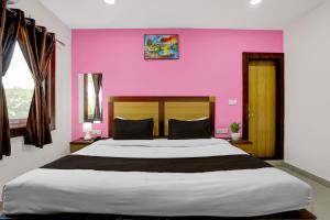 Hotel O Varanasi Trade Center formerly Vairaghi Villa في فاراناسي: غرفة نوم بسرير كبير وبجدار وردي +27 صورة