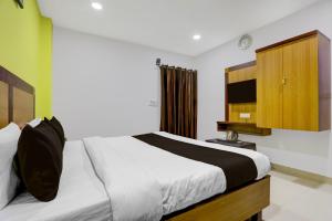 Hotel O Varanasi Trade Center formerly Vairaghi Villa في فاراناسي: غرفة نوم مع سرير وخزانة خشبية