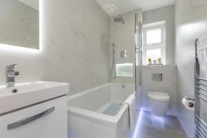 a white bathroom with a tub and a sink at Stanley House in Reading