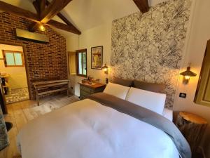 Un dormitorio con una gran cama blanca y una pared de ladrillo en Domaine de la Gare - La Lampisterie, en Nibelle