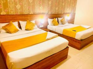 two beds in a hotel room with yellow pillows at THE CITY PARK HOTEl in Hyderabad