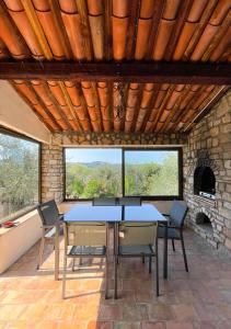 Provençal farmhouse 6 guests Peymeinade near Cannes في Peymeinade: طاولة وكراسي في غرفة مع موقد حجري