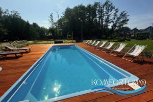 a swimming pool on a deck with lounge chairs at Domek w Baltic Natur Park Komfortowy 2 sypialnie klima alpaki mnóstwo atrakcji by DG in Niechorze