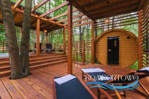 a wooden cabin with a table and chairs on a deck at Domek w Baltic Natur Park Komfortowy 2 sypialnie klima alpaki mnóstwo atrakcji by DG in Niechorze