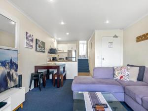 Una sala de estar con un sofá morado y una mesa en Cascades 15 - Amazing Lake Views l Spa Bath l Split Level Apt l Central Location l Wi-Fi, en Jindabyne