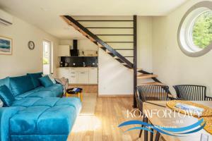a living room with a blue couch and a staircase at Domek w Baltic Natur Park Komfortowy 2 sypialnie klima alpaki mnóstwo atrakcji by DG in Niechorze