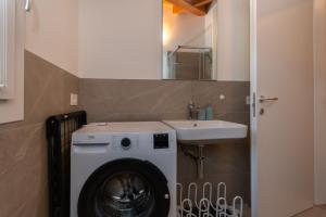 een badkamer met een wasmachine en een wastafel bij Hapina Dolomiti in Cencenighe +23 foto's