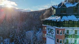 a building in the snow with the sun in the background at Hotel Las Piechowice in Szklarska Poręba