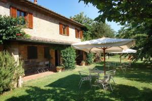 a table and chairs with an umbrella in front of a house at La Cerretola in Città della Pieve
