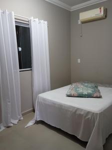 Schlafzimmer mit einem Bett und einem Fenster mit weißen Vorhängen in der Unterkunft Casa bananeira in Bombinhas + 5 Fotos