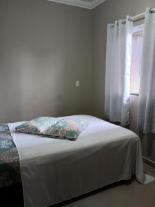 ein Schlafzimmer mit einem Bett mit zwei Kissen und einem Fenster in der Unterkunft Casa bananeira in Bombinhas