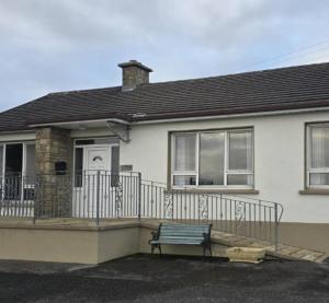 a white house with a bench in front of it at Harkins Haven in Mountcharles