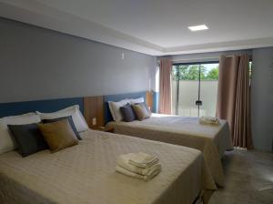 Dos camas en una habitación de hotel con toallas encima. en Apart hotel Corbari, en Ametista do Sul