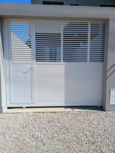 eine weiße Garagentür mit Fenstern auf einem Haus in der Unterkunft Casa bananeira in Bombinhas