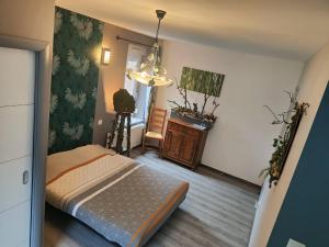a bedroom with a bed and a table and a chair at l'Adapté in Raon-lʼÉtape