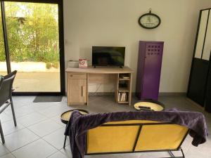 La PASSUITIÈRE في Saint-Mesmin: غرفة بها مكتب وتلفاز وساعة