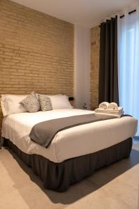 1 cama grande en un dormitorio con pared de ladrillo en Apartamentos Baños, 6 CAROLA, en Linares