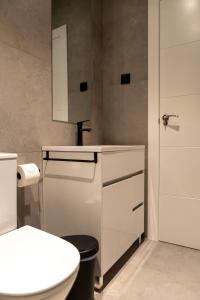 Un baño con lavabo blanco y inodoro. en Apartamentos Baños, 6 CAROLA, en Linares