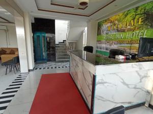 a red carpet in a lobby with a welcome to a hotel at Royel IN Hotel in Mund Pīr Mahmūd