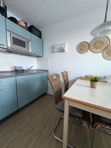 Una cocina con gabinetes azules y una mesa con sillas. en Familienauszeit mit Indoorpool, Sauna, Netflix, Disney, 50-100 MBit Internet inkl Bettwäsche Handtücher Reinigung, en Missen-Wilhams