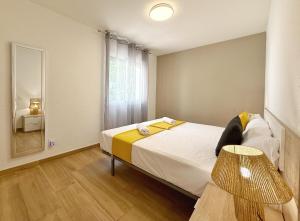 a bedroom with a bed with a mirror and a lamp at DOMuum Holidays - DELFOS in Salou