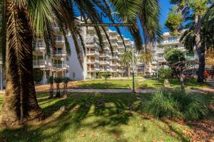 an apartment building with palm trees in a park at DOMuum Holidays - DELFOS in Salou