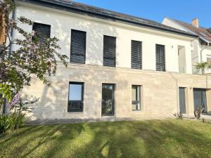 a large white building with windows and a yard at Duna-Part Deluxe in Vác