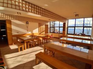 a restaurant with tables and benches and windows at Tau Forest Lodge in Solkan