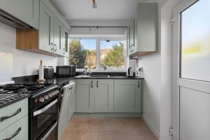 a kitchen with white cabinets and a window at Exeter Heights - Short Stays UK Ltd in Exeter
