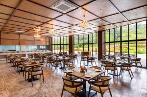 Osian Valley Resort & Spa Kumbhalgarh في Jāmb: غرفة طعام مع طاولات وكراسي ونوافذ