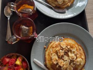 a table with two plates of pancakes and a bowl of fruit at Mila Homestay in Padang +23 photos