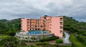 Osian Valley Resort & Spa Kumbhalgarh في Jāmb: مبنى وردي أمامه مسبح