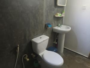 a bathroom with a white toilet and a sink at Whispering Wind Yala in Kirinda