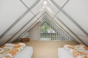 two beds in a attic room with a window at Feriehus 1133 in Ringkøbing
