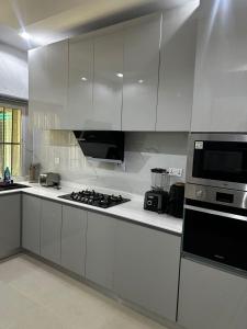 a kitchen with white cabinets and a stove top oven at Modern 3-Bedroom Luxury Home in Lekki Phase 1 in Lekki