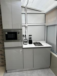 a white kitchen with a stove and a microwave at Modern 3-Bedroom Luxury Home in Lekki Phase 1 in Lekki +9 photos
