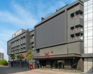 a large gray building with palm trees in front of it at Radisson RED Izmir Point Bornova in İzmir