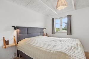 a bedroom with a large white bed with a window at Feriehus 1142 in Ringkøbing