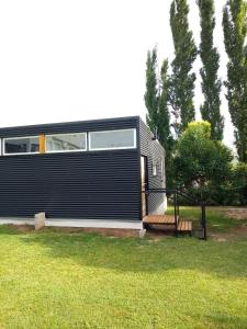 a black house with a bench in a yard at Tiny House Potrero Cba in Potrero de Garay
